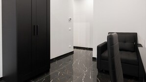 Une chambre moderne avec une armoire noire, un fauteuil noir et un sol en marbre.
