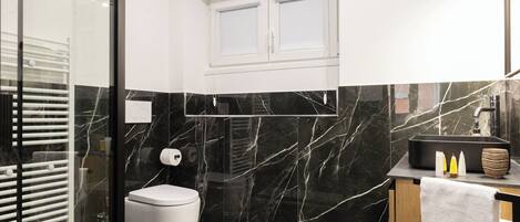 A modern bathroom with a toilet, a shower, and a sink.