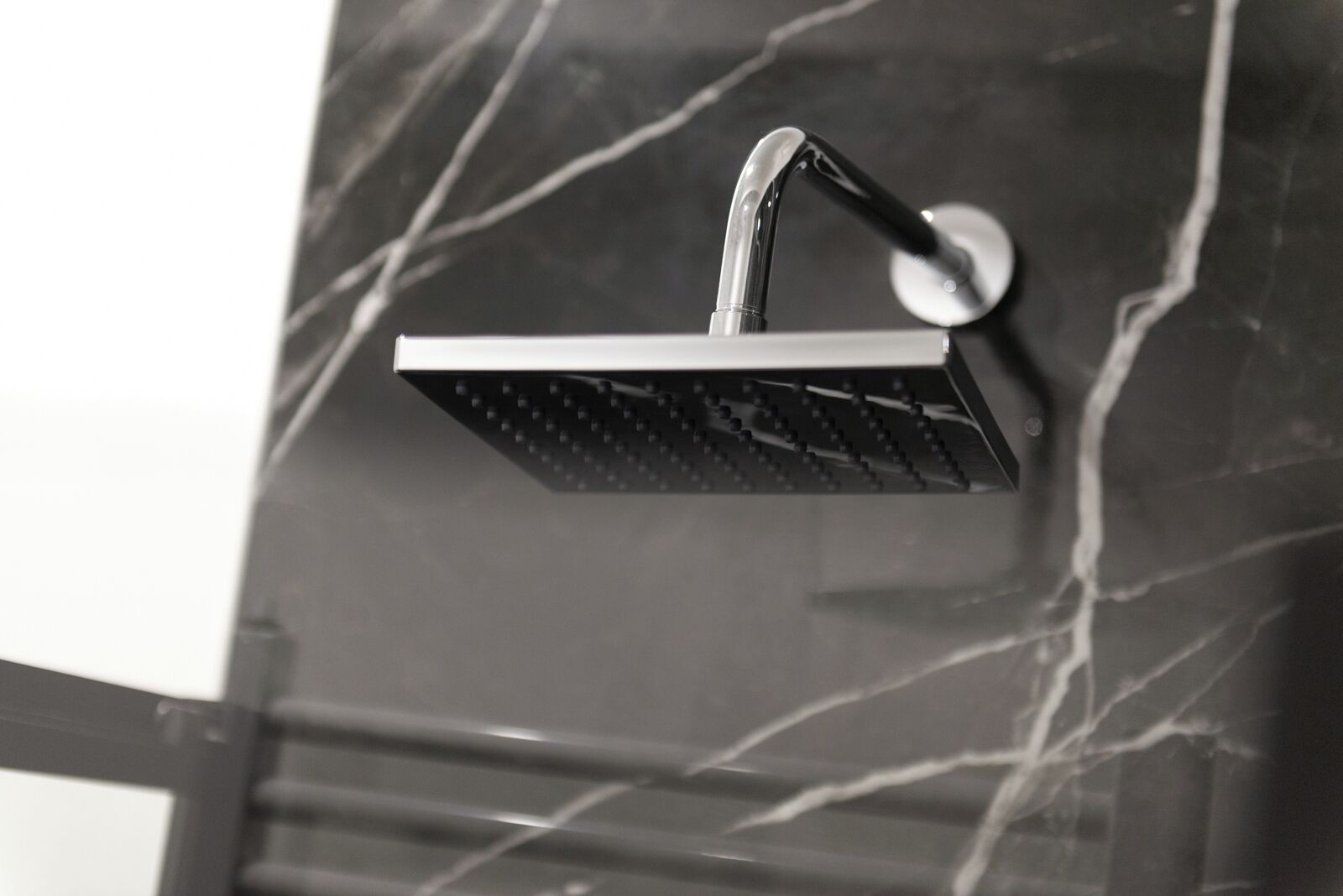 A modern showerhead with a sleek, curved design mounted on a marble wall.