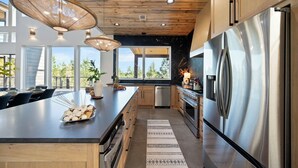 Una cocina moderna con una isla grande, electrodomésticos de acero inoxidable y techo de madera.