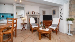 Una sala de estar con chimenea, televisor y comedor con sillas y mesa.