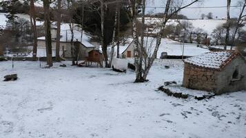 Un paysage enneigé avec un bâtiment en pierre, une structure en bois et une zone délimitée par une clôture.