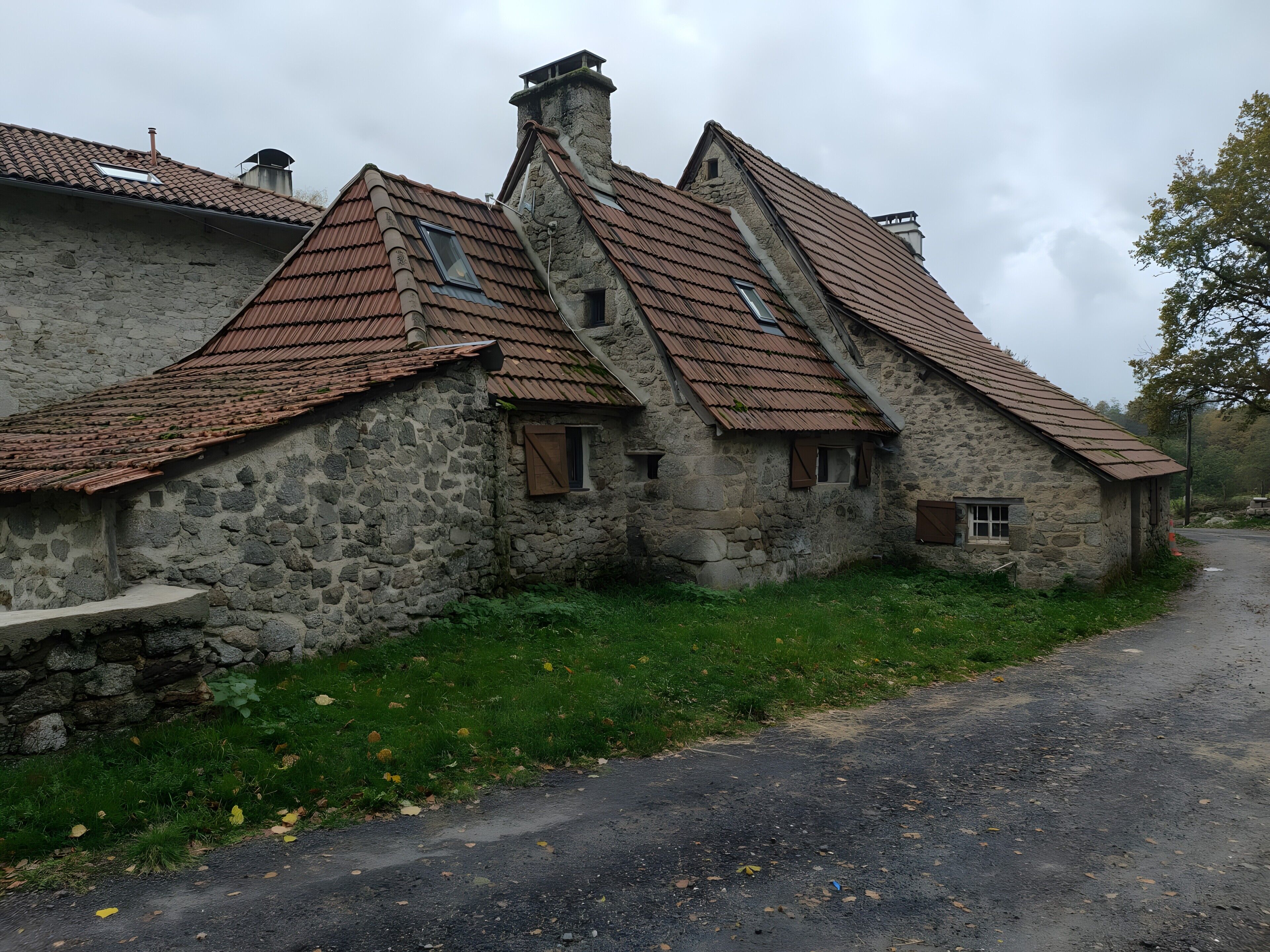 A stone building with a sloped roof, a chimney, and a small window.