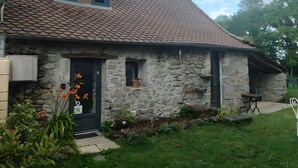 Una casa de piedra con techo de tejas, un porche pequeño y una puerta principal.