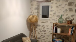 Una sala de estar con un sofá, una lámpara de pie, una estantería y una alfombra estampada.