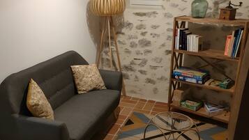 A living room with a sofa, a floor lamp, a bookshelf, and a patterned rug.