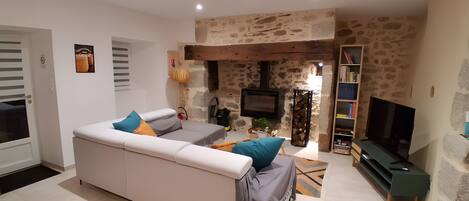 A living room with a sofa, television, and stone wall.