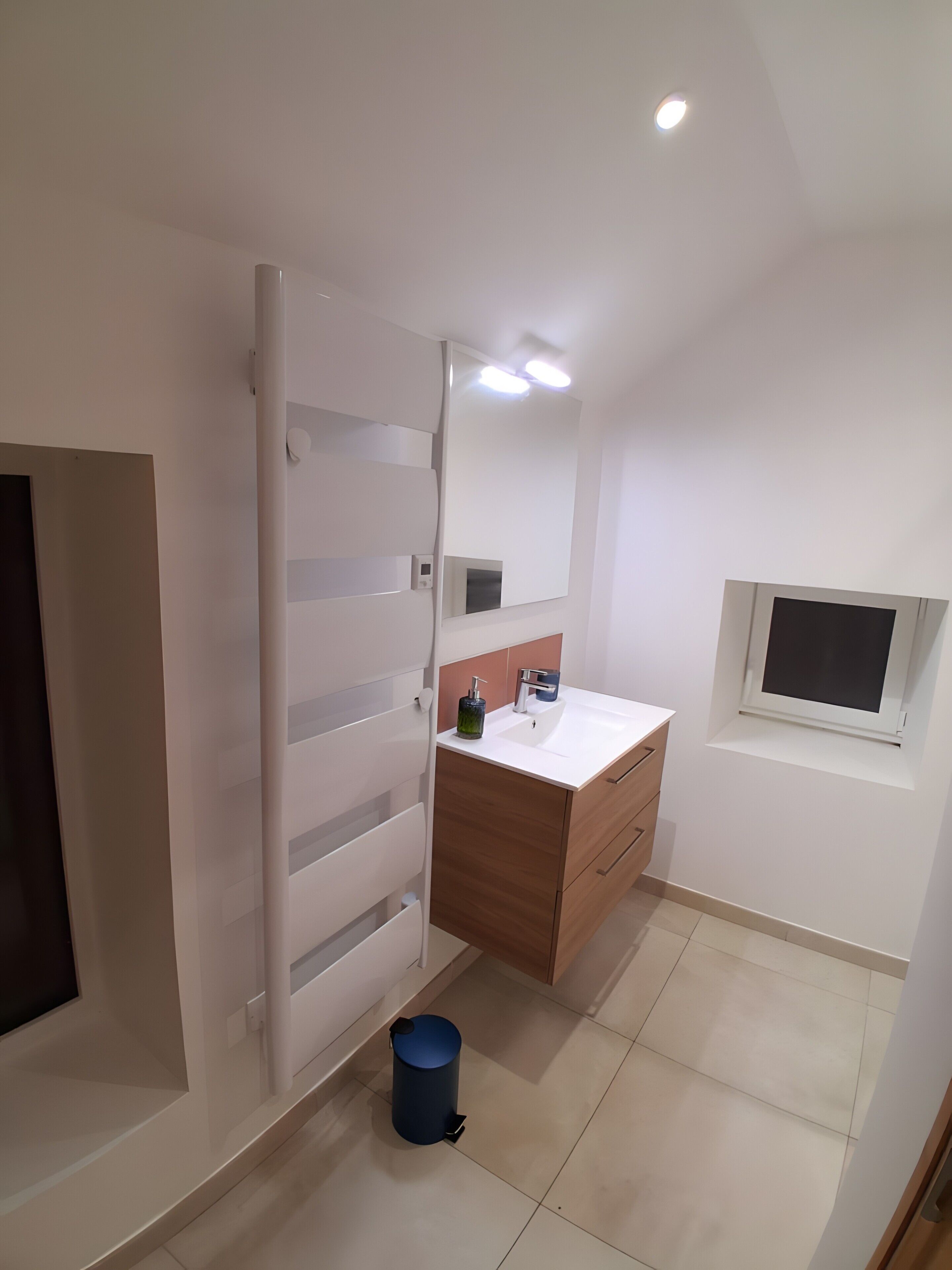 Une salle de bain moderne avec un meuble-lavabo blanc, un miroir et une fenêtre.