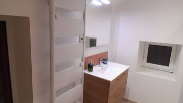 Un baño moderno con un tocador blanco, un espejo y un ventanal.