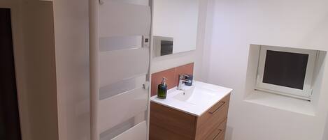 Une salle de bain moderne avec un meuble-lavabo blanc, un miroir et une fenêtre.