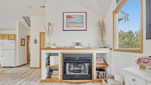 A modern kitchen with a built-in fireplace, wooden cabinetry, and a large window offering a view of the outdoors. - Golf & Surf 7BR: Private Pool, 5 Min to Beach (Corolla)
