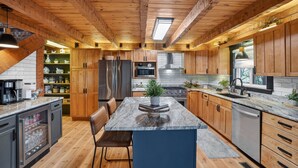 A modern kitchen with wooden cabinets, a central island, and a built-in oven. - Pine Mountain Lodge Game Room & Wrap-around Porch 5 Bedroom Cabin (Connellys Springs)