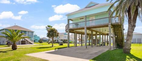 A beachfront property with a covered patio, a pool, and a two-story building.