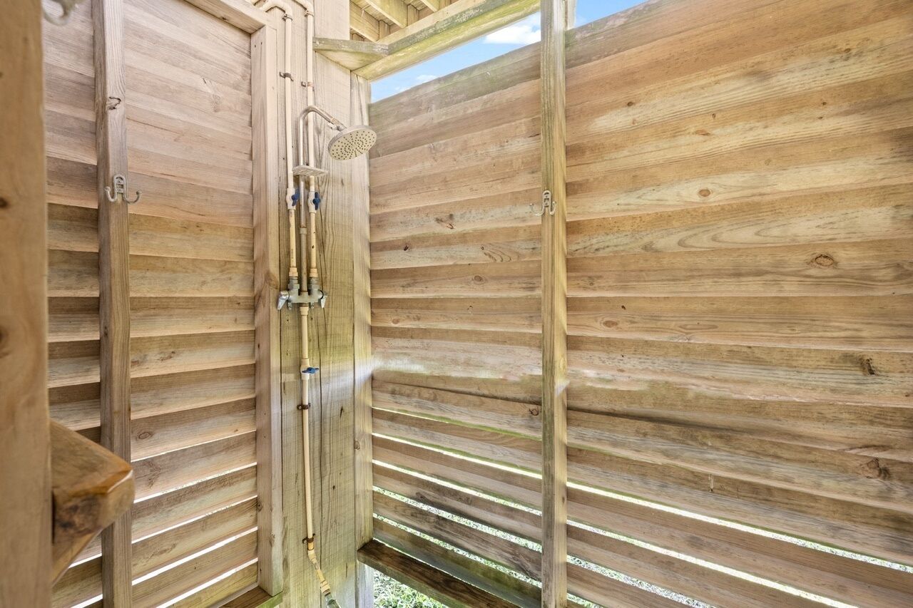 A wooden interior with a shower area, visible plumbing, and a window allowing natural light.