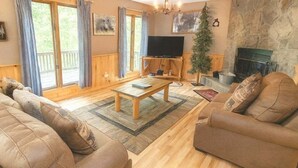 A cozy living room with a wooden coffee table, two sofas, a television, and a fireplace. - Wandering Bear Lodge 4 Bedroom Cabin (Sevierville)