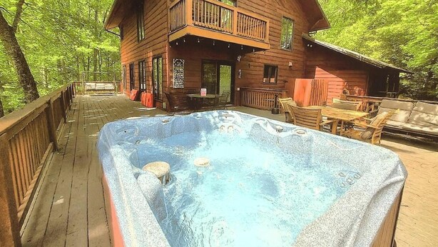 A wooden cabin with a hot tub on a deck surrounded by trees. - Wandering Bear Lodge 4 Bedroom Cabin (Sevierville)