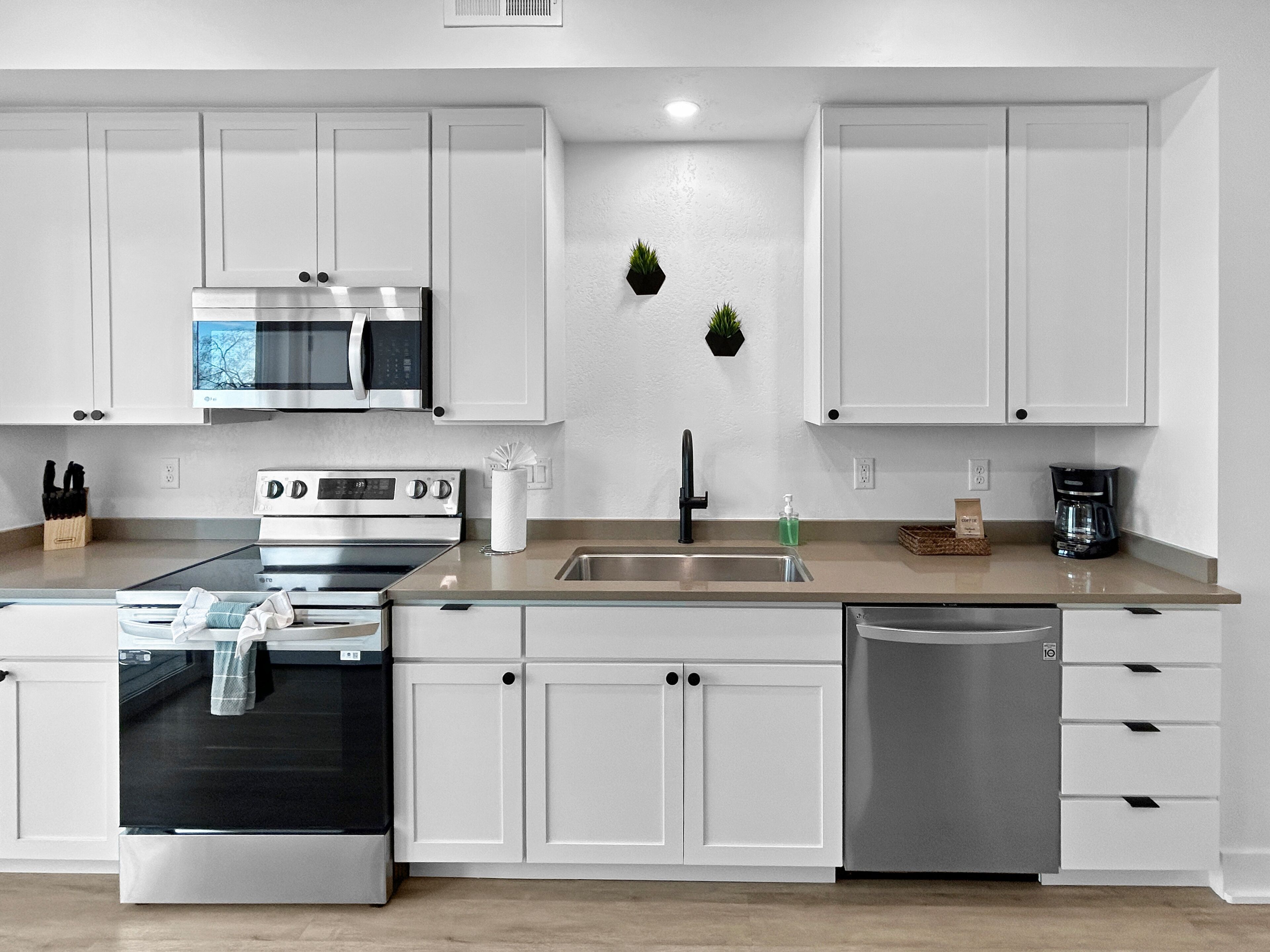 A modern kitchen with white cabinetry, stainless steel appliances, and a central island.