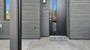 A modern building entrance with a dark wooden facade, a numbered door, and a welcome mat. - Terrace At Two Rivers 3 Bedroom Townhouse (Grand Junction)