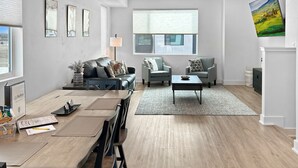 A modern living room with a dining area, featuring a sofa, armchairs, a coffee table, and a dining table with chairs. - Terrace At Two Rivers 3 Bedroom Townhouse (Grand Junction)
