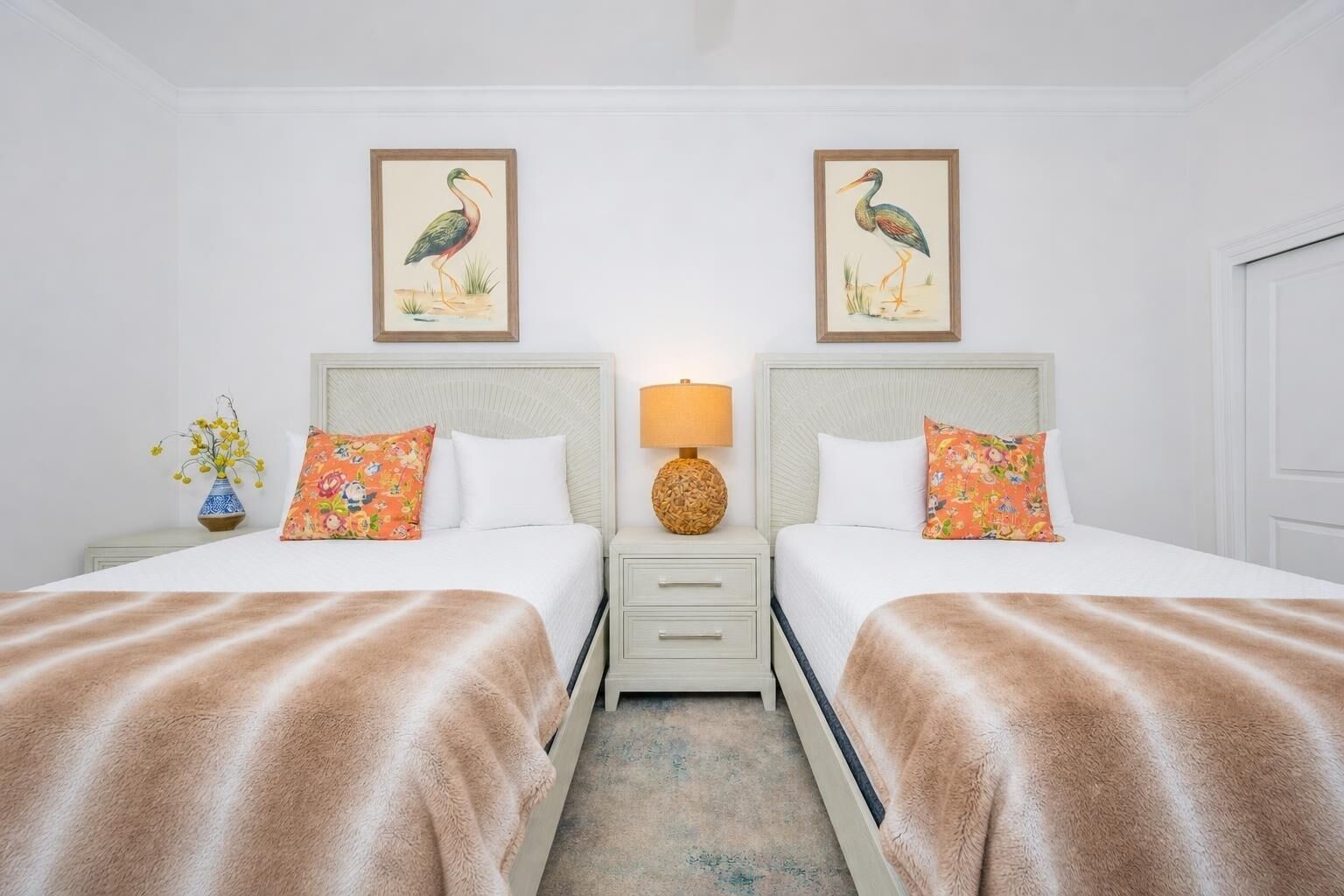 Une chambre d’hôtel avec deux lits, une table de chevet avec une lampe et des œuvres d’art murales.