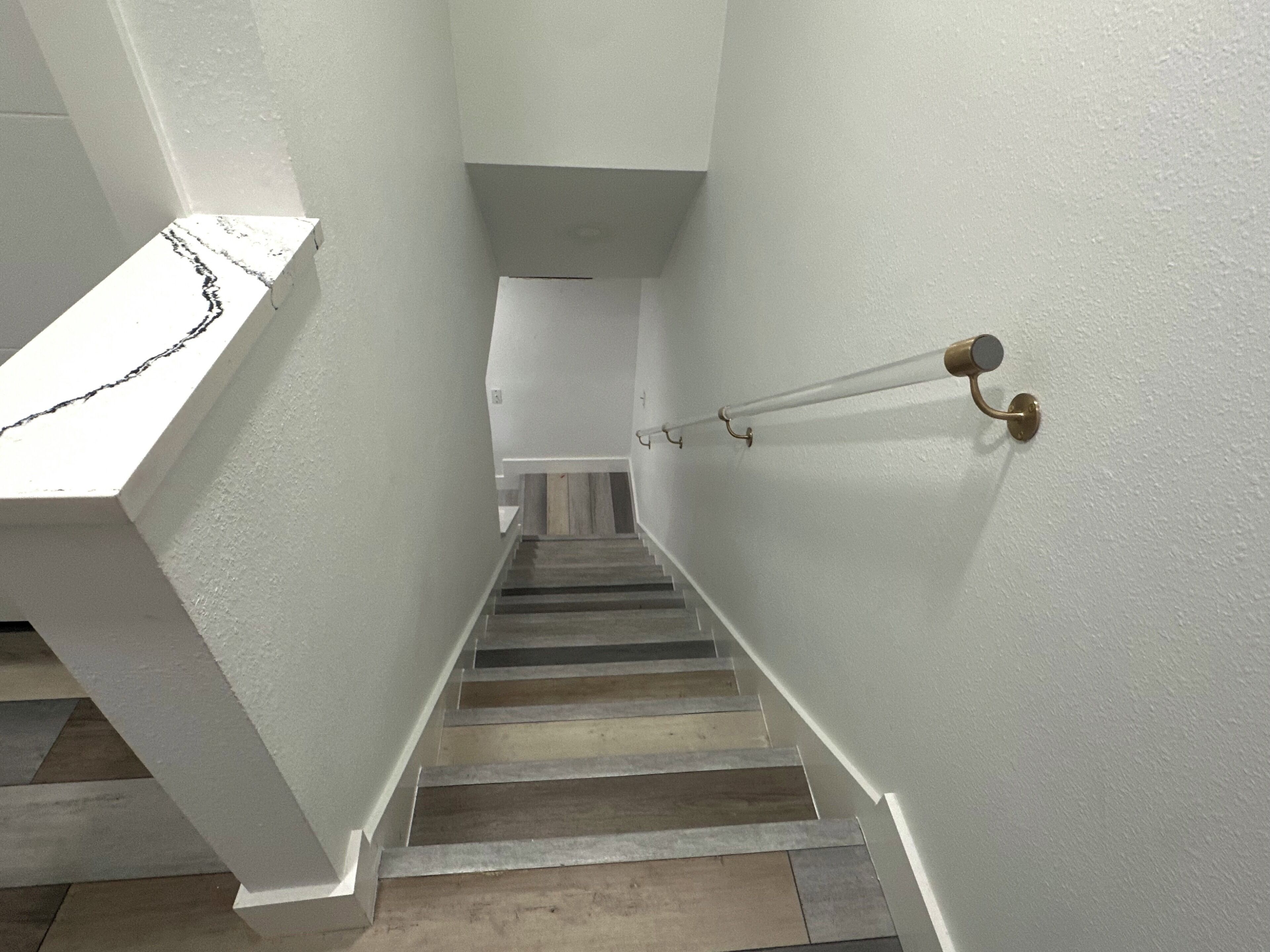 Un escalier avec des murs blancs et un plancher en bois.