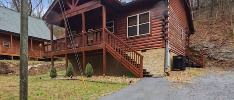 A log cabin with a balcony and a stone foundation.