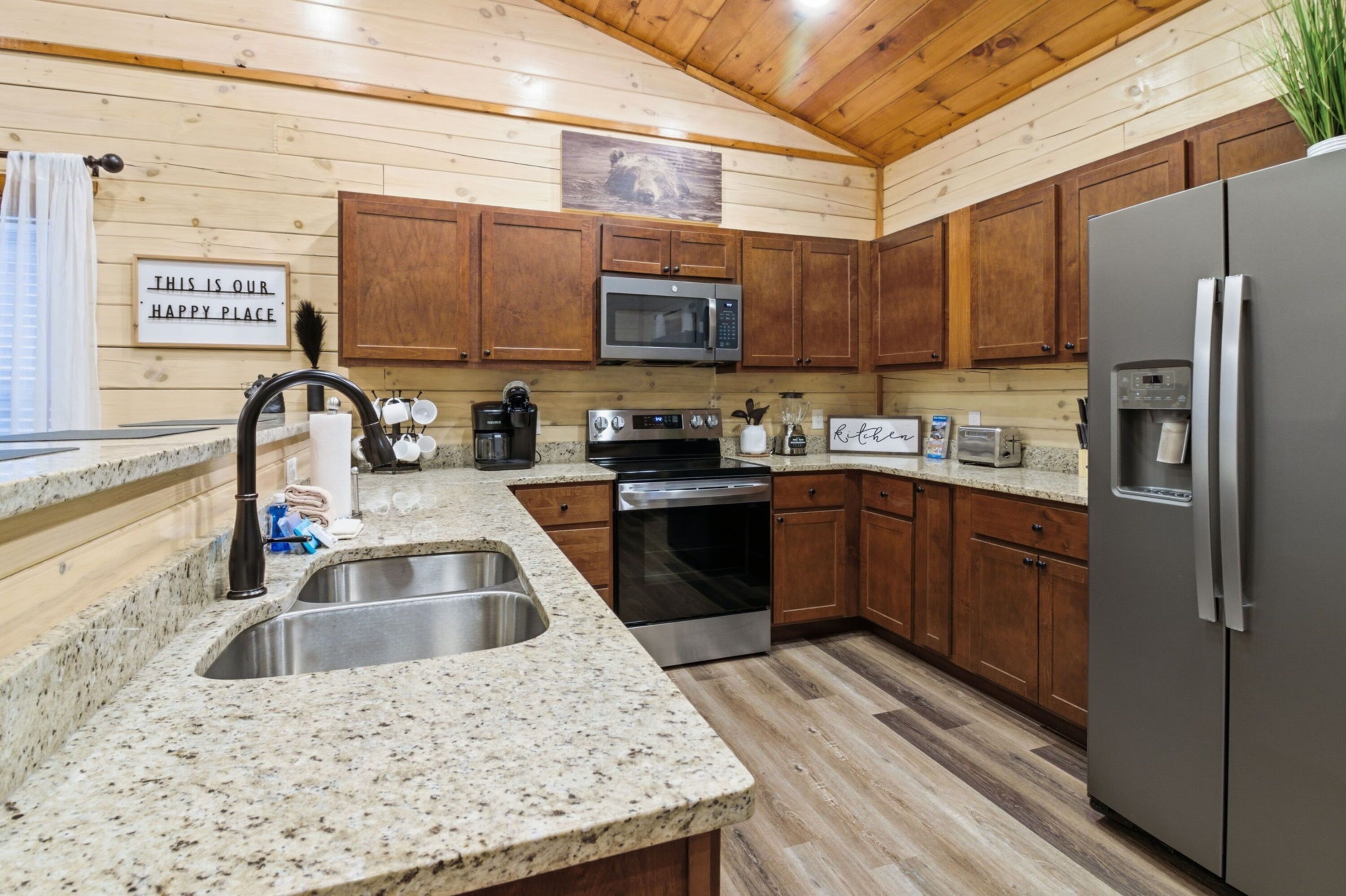 A kitchen with granite countertops, stainless steel appliances, wooden cabinets, and a microwave above the oven.