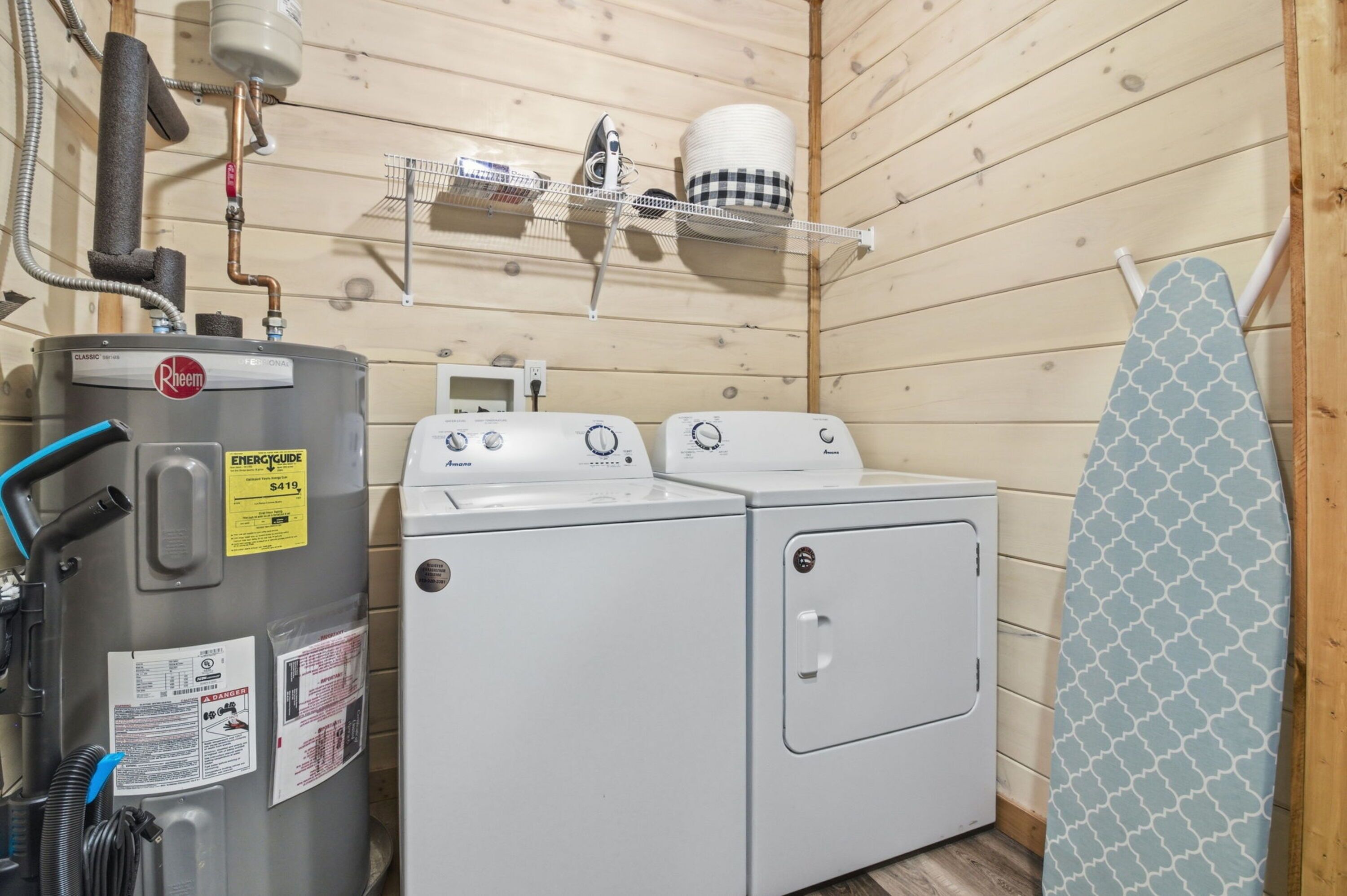 A laundry area with a washer and dryer, a water heater, and a shelf with laundry supplies.