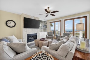 A living room with a fireplace, sofas, a coffee table, and a TV. - Beach Please + Casita (Wrightsville Beach)
