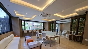 A modern office space with a long table, several chairs, a sofa, and a large window. - Apartaestudio Shanty Tipo 1 (Barranquilla)