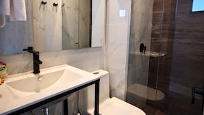 A modern bathroom with a marble vanity, a glass shower enclosure, and a toilet. - Apartaestudio Shanty Tipo 1 (Barranquilla)