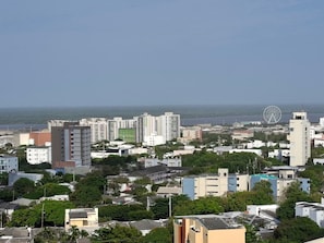 A coastal cityscape with high-rise buildings, a Ferris wheel, and a clear view of the sea. - Apartaestudio Shanty Tipo 1 (Barranquilla)