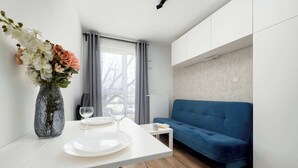 Un soggiorno moderno con un tavolo bianco, un divano blu e un vaso di fiori.