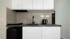 Una cucina moderna con mobili bianchi, un'lavastoviglie nera, un lavello e un bollitore.