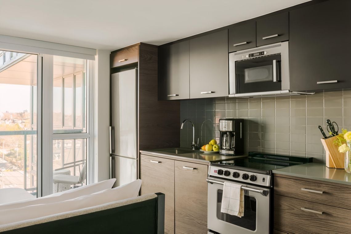 Een moderne keuken met een koelkast, magnetron, fornuis en koffiezetapparaat.