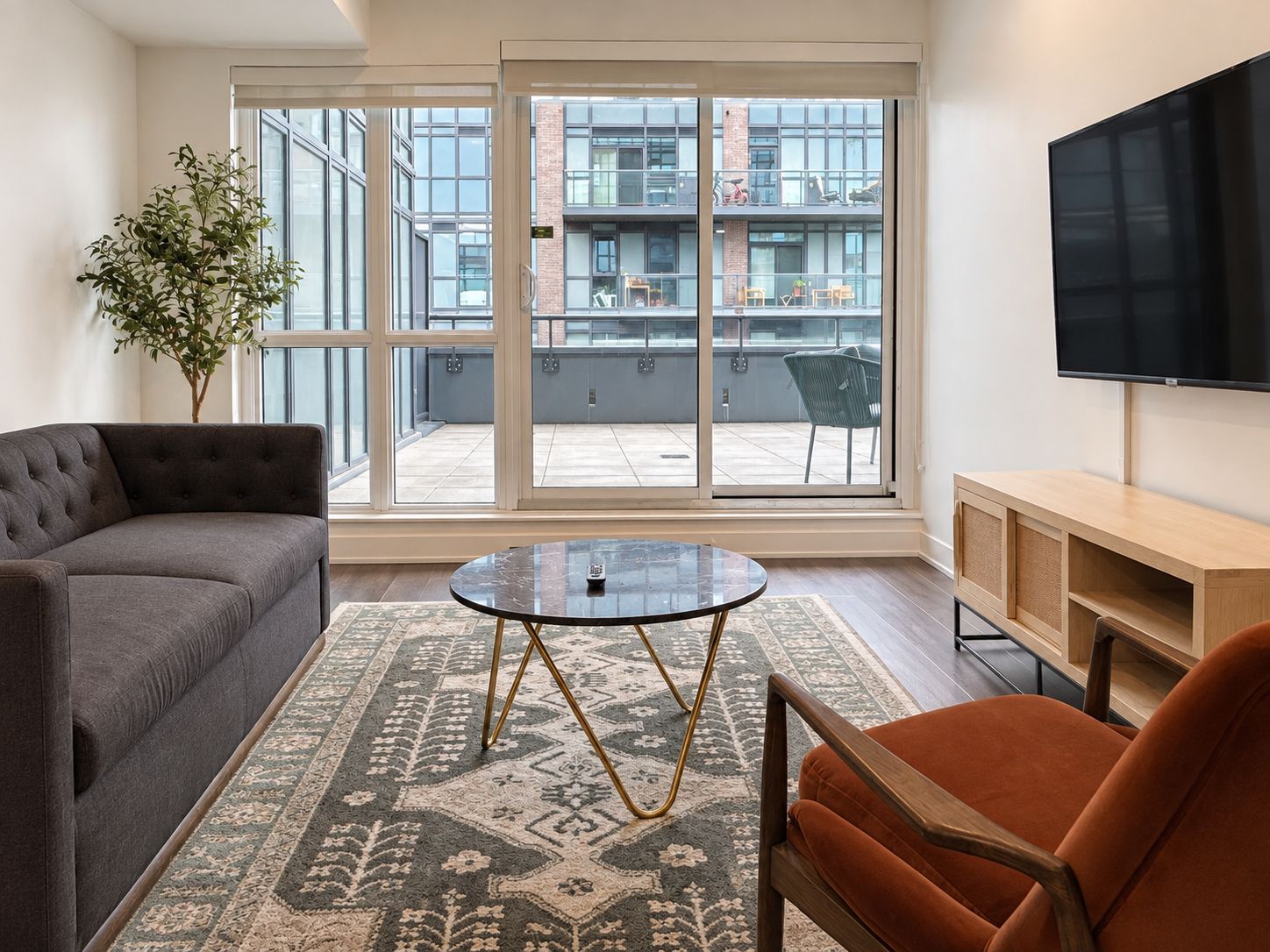 A modern living room with a grey sofa, a round coffee table, and an orange armchair.
