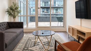 A modern living room with a grey sofa, a round coffee table, and an orange armchair.
