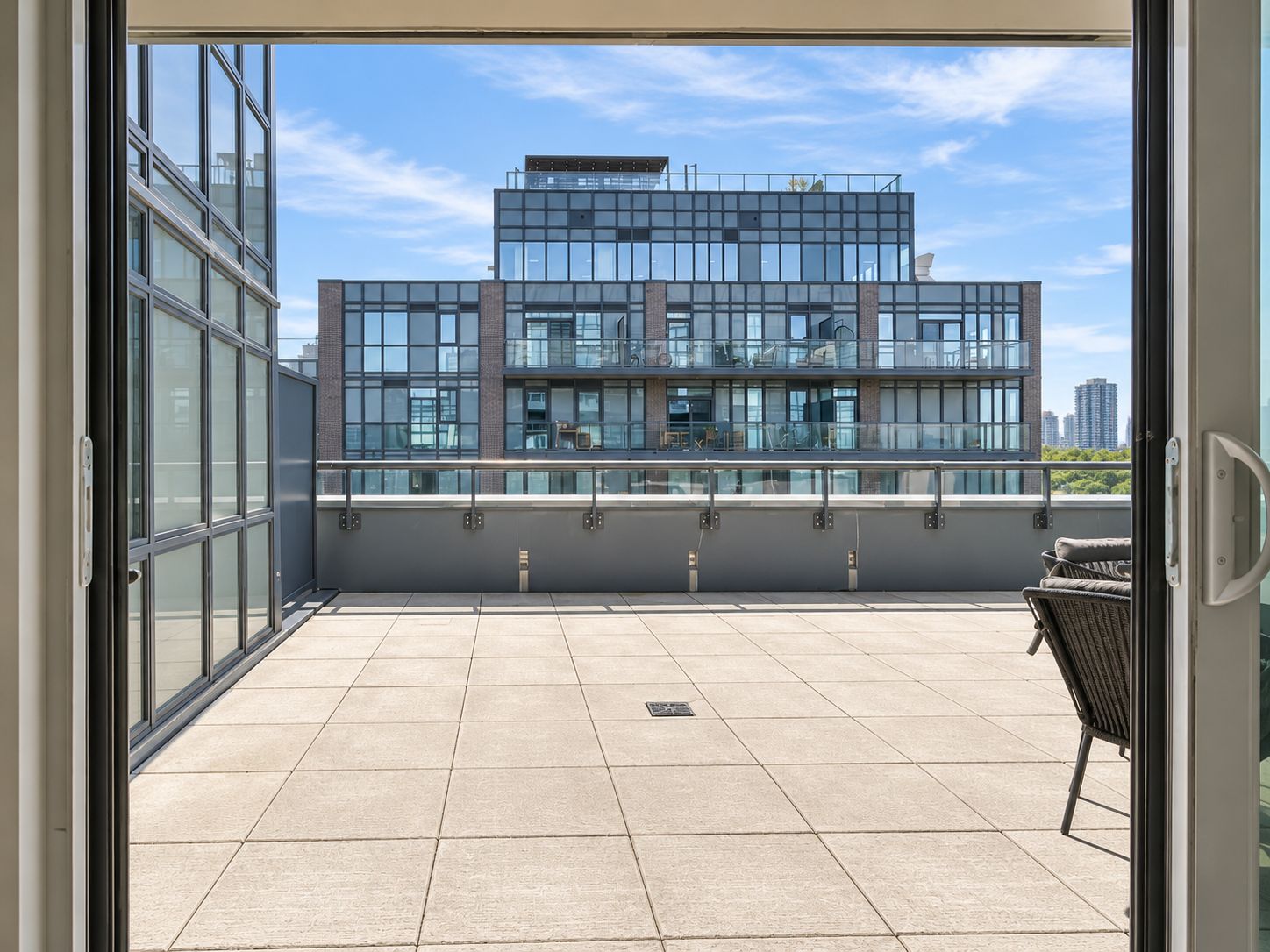 A modern building with large windows and a balcony with outdoor furniture.