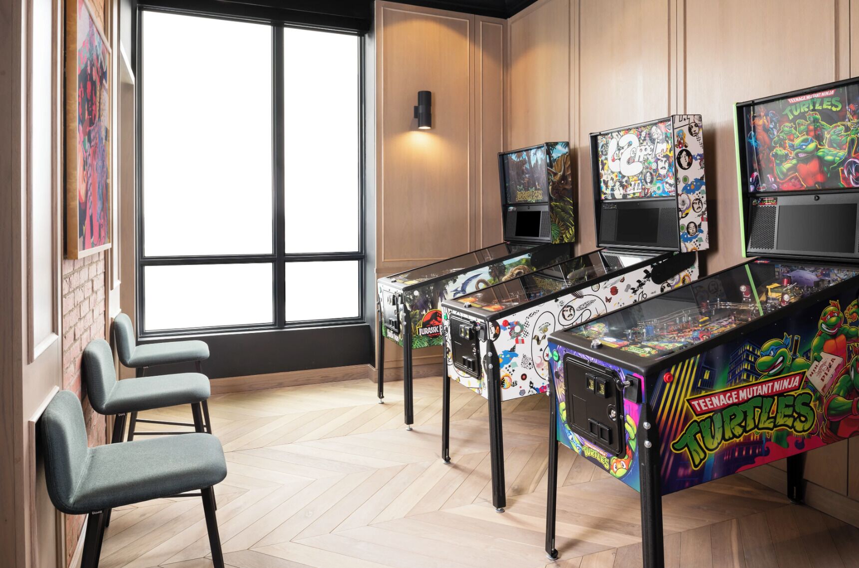 A room with arcade machines, a large window, and a wall-mounted light.