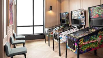 A room with arcade machines, a large window, and a wall-mounted light.