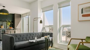Een moderne woonkamer met een grijze bank, een klein rond tafeltje en een groene stoel.
