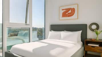 Een moderne slaapkamer met een groot bed, een nachtkastje, een kunstwerk in een lijst en uitzicht op de stad.