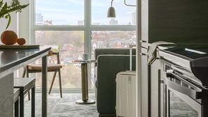 Een moderne keuken met uitzicht op de stad, een eethoek met een tafel en stoelen, en een groot raam.