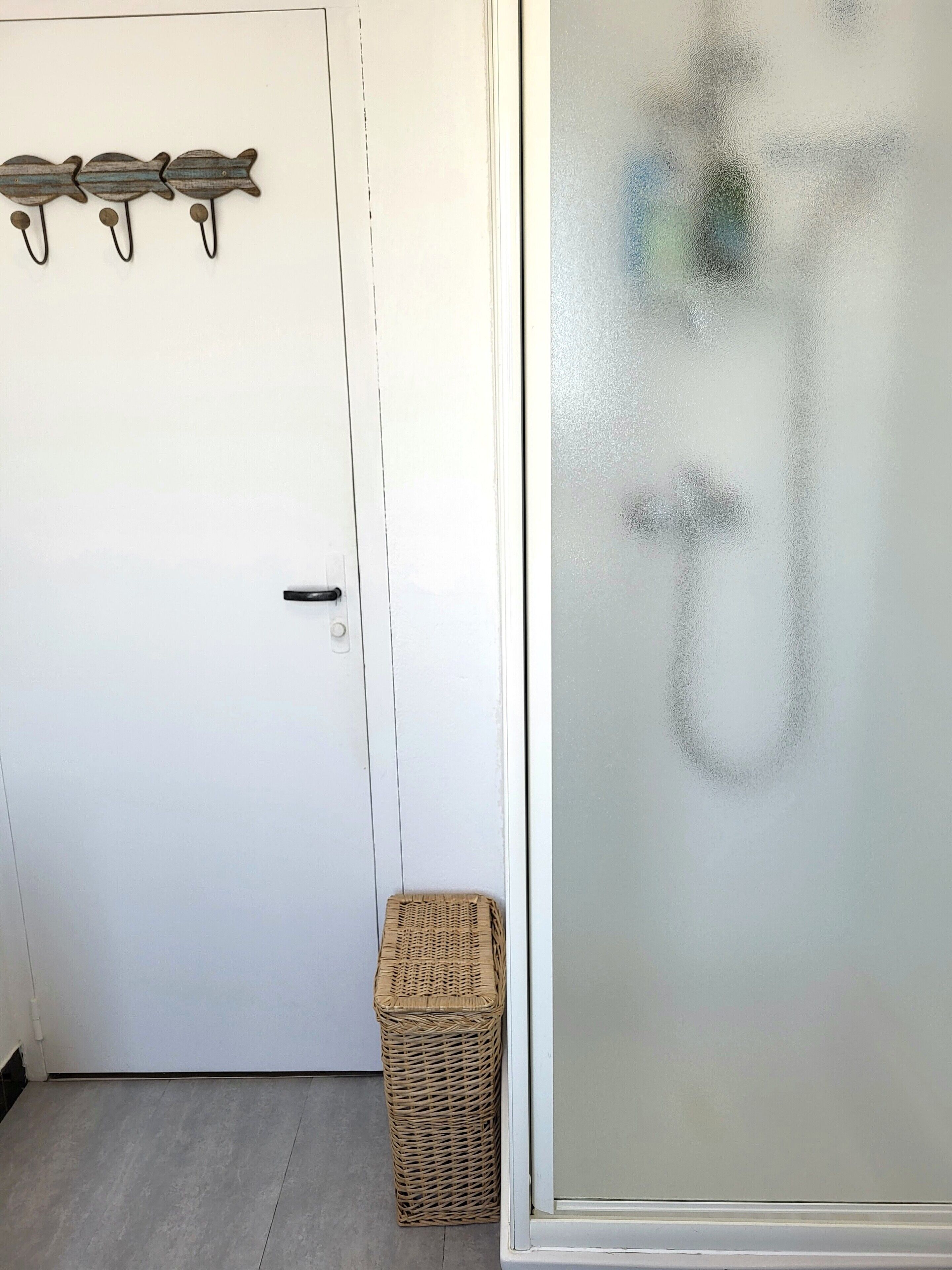 Une porte blanche avec une poignée, un panier en osier et une fenêtre en verre dépoli.