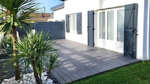 A modern house with a patio, a white exterior, and shutters on the windows. - Holiday Home "La Villa Kikifil, Seaside" with Private Terrace, Garden & Wi-Fi (Saint-Germain-sur-Ay)