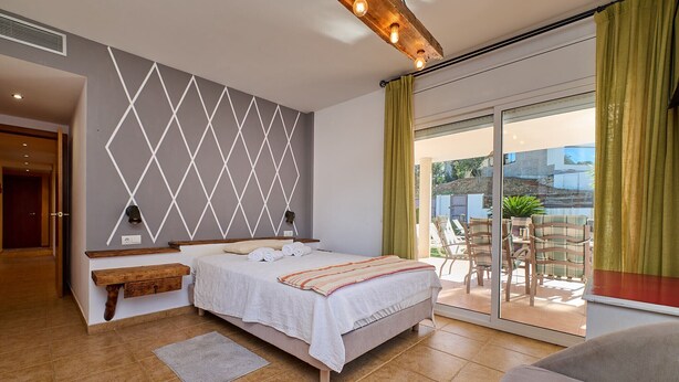 A bedroom with a bed, a bedside table, a wall-mounted light, and a view of the outside balcony. - 1Mel01 - House with private pool for 7 people near one of the most beautiful beaches in Begur (Begur)