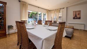 A dining area with a table set for four, wicker chairs, and a view of the outdoors. - 1Mel01 - House with private pool for 7 people near one of the most beautiful beaches in Begur (Begur)