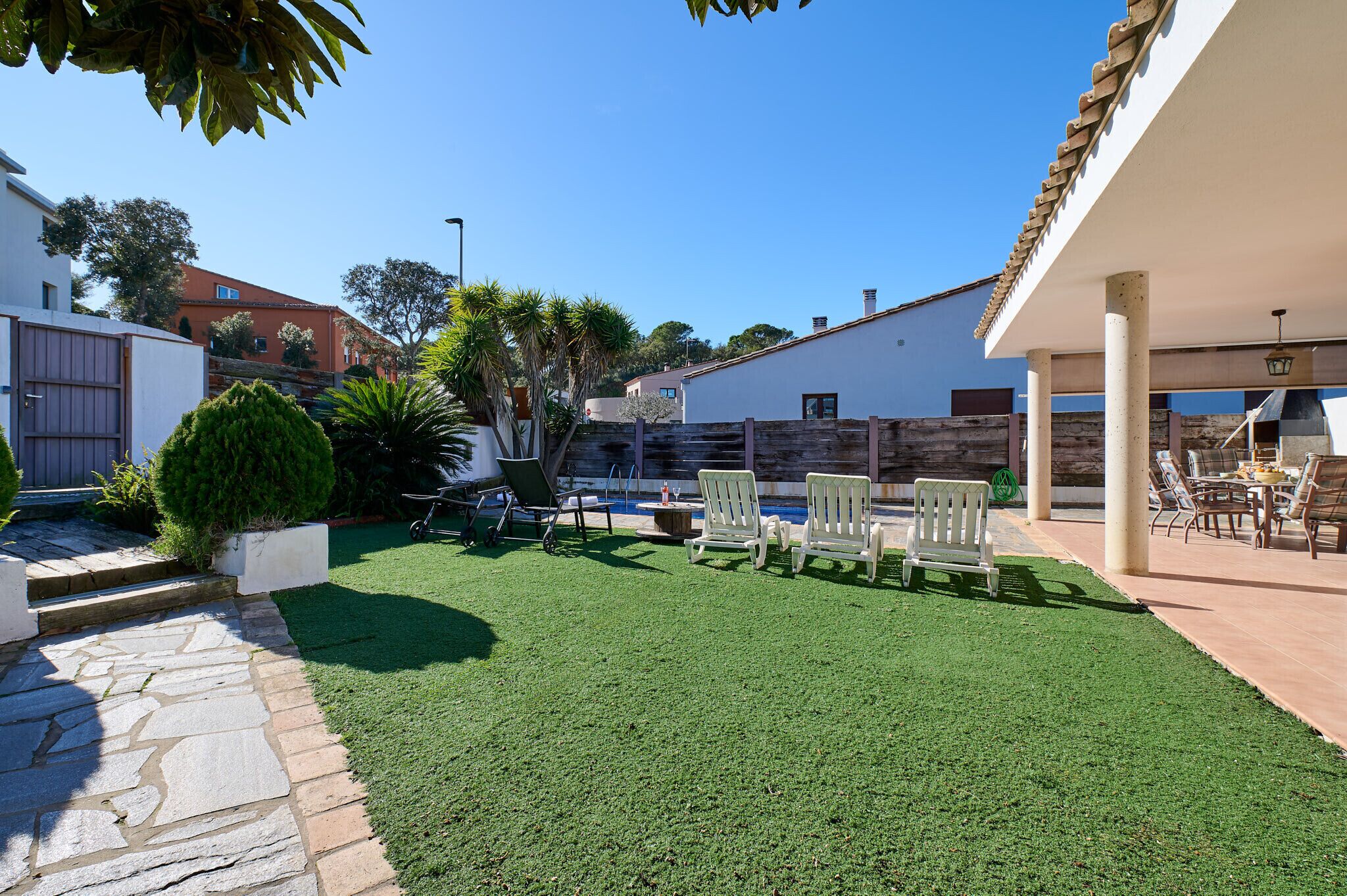 A patio area with artificial grass, outdoor furniture, and a stone pathway.