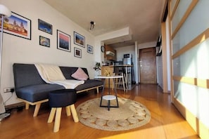A modern living room with a sofa, a small round table, and a kitchen in the background. - Luminous refuge with panoramic view in the heart of Santiago (Santiago)