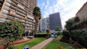 Une cour avec un chemin, des palmiers et un bâtiment à plusieurs étages doté de balcons.